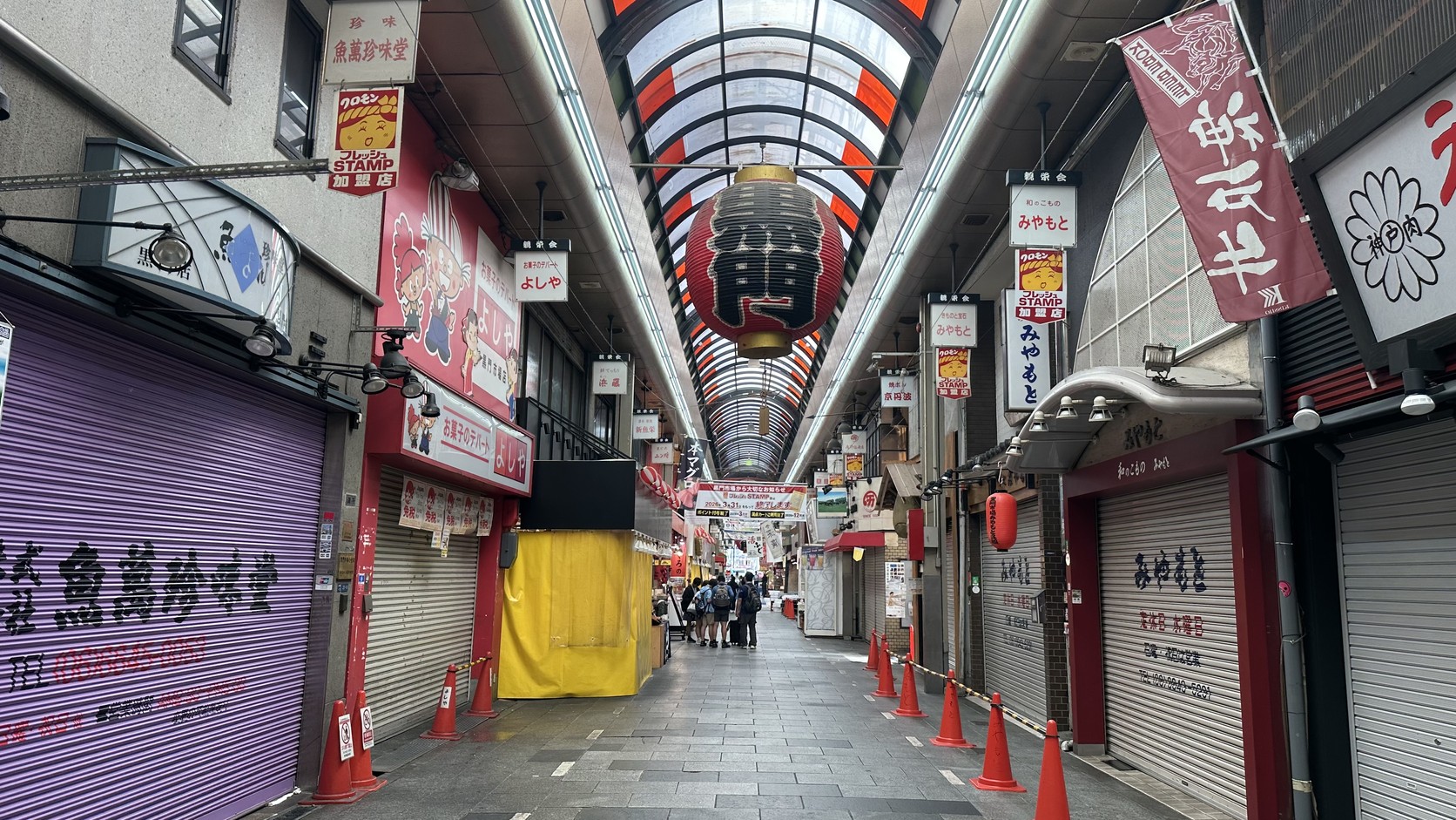 清晨的有頂拱廊往遠處延伸，兩側店家鐵門多半關著，通道相當空曠