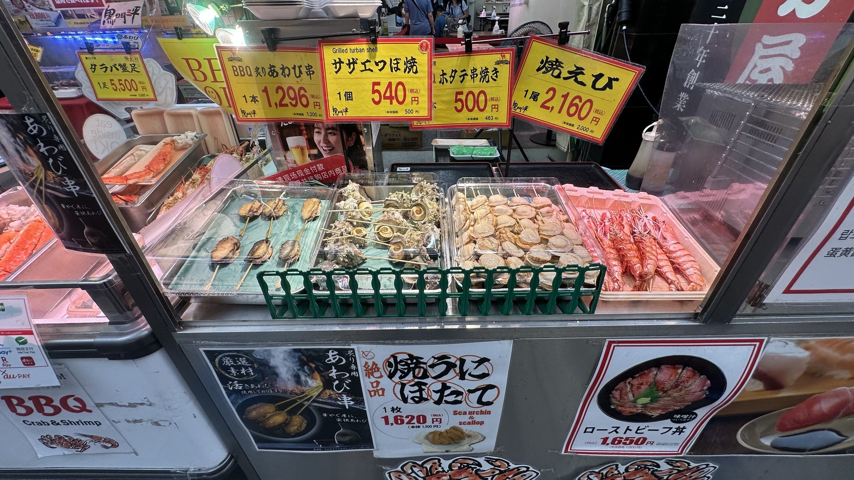 黑門三平的現烤海鮮攤，擺著扇貝、牡蠣與蝦，旁邊掛著標價牌
