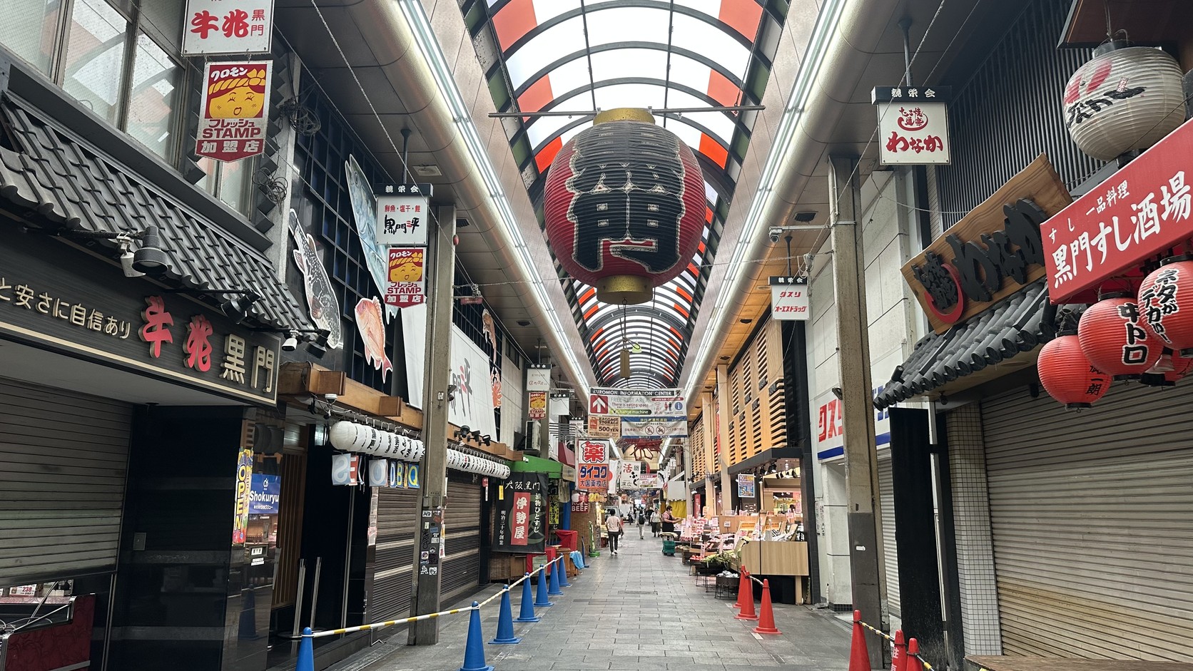黑門市場的長拱廊與紅色「門」字大燈籠，兩側店家的鐵門多半仍關著
