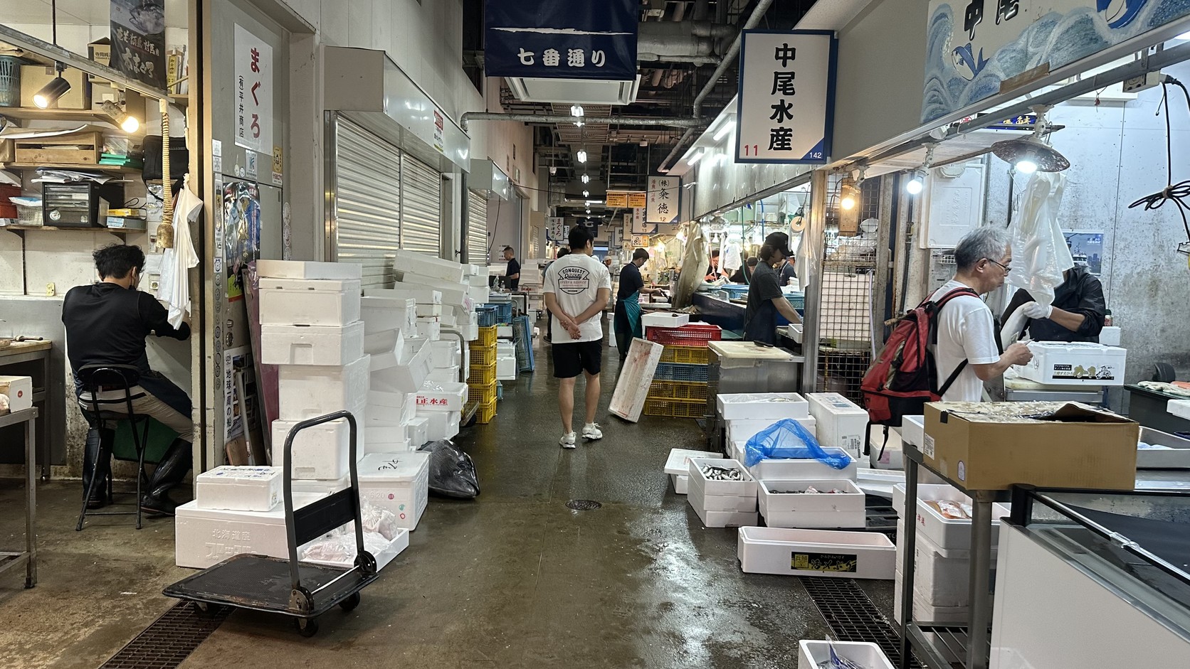 七番通的通道，店家門口堆放著保麗龍箱，地面濕潤