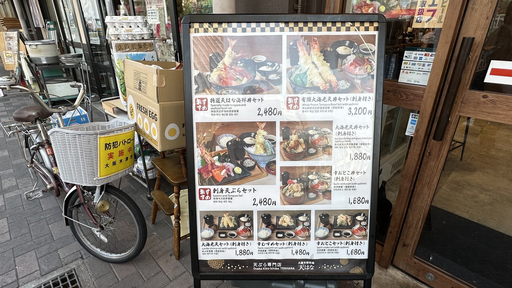 天はな門口的菜單看板，旁邊玻璃門貼有信用卡與行動支付標示
