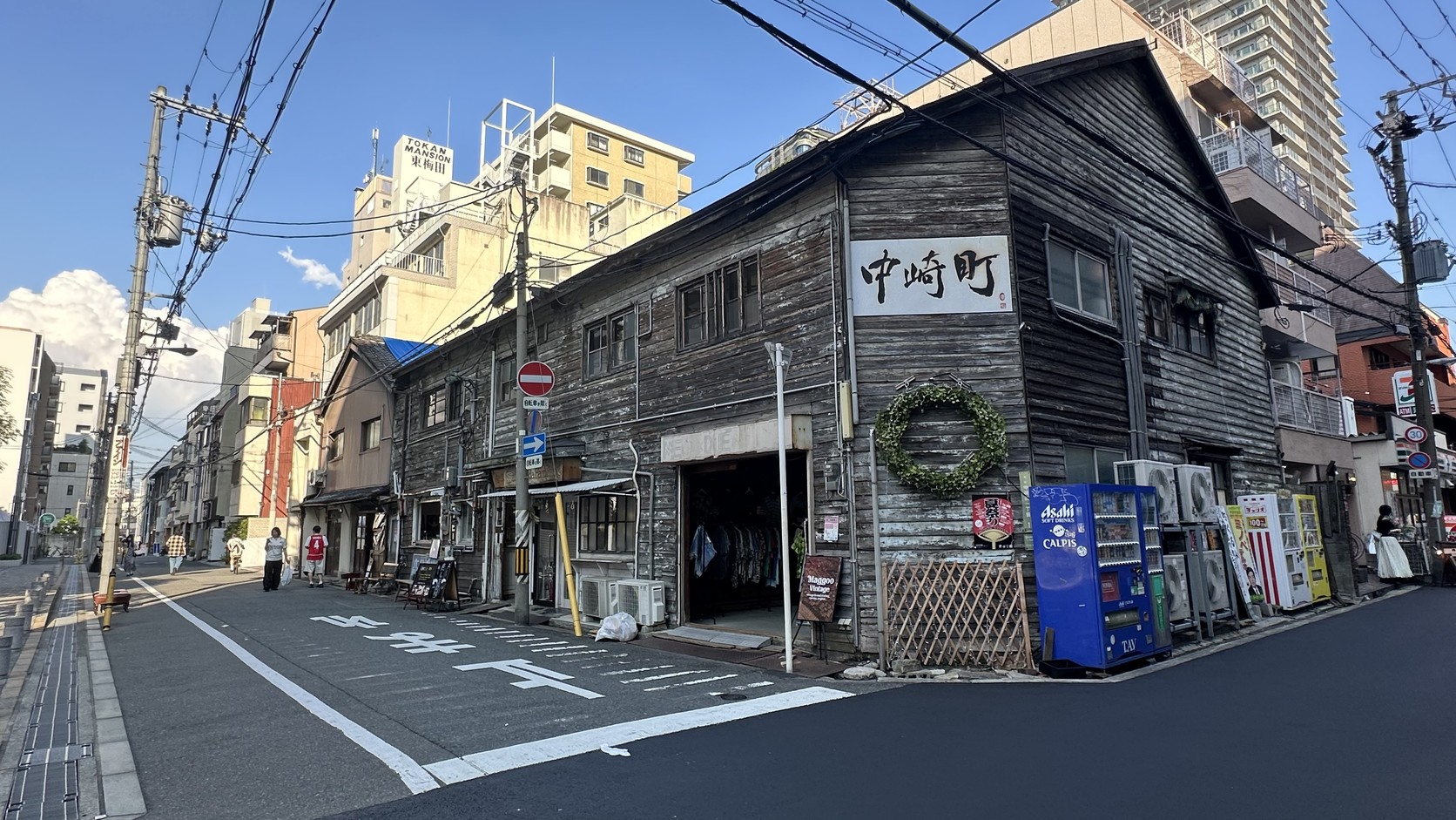 外牆掛著「中崎町」招牌的灰黑色木造老建築，旁邊有自動販賣機與冷氣室外機