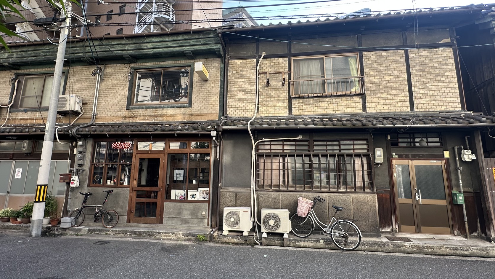 磚造與木造外牆混合的連棟長屋，門前停著腳踏車