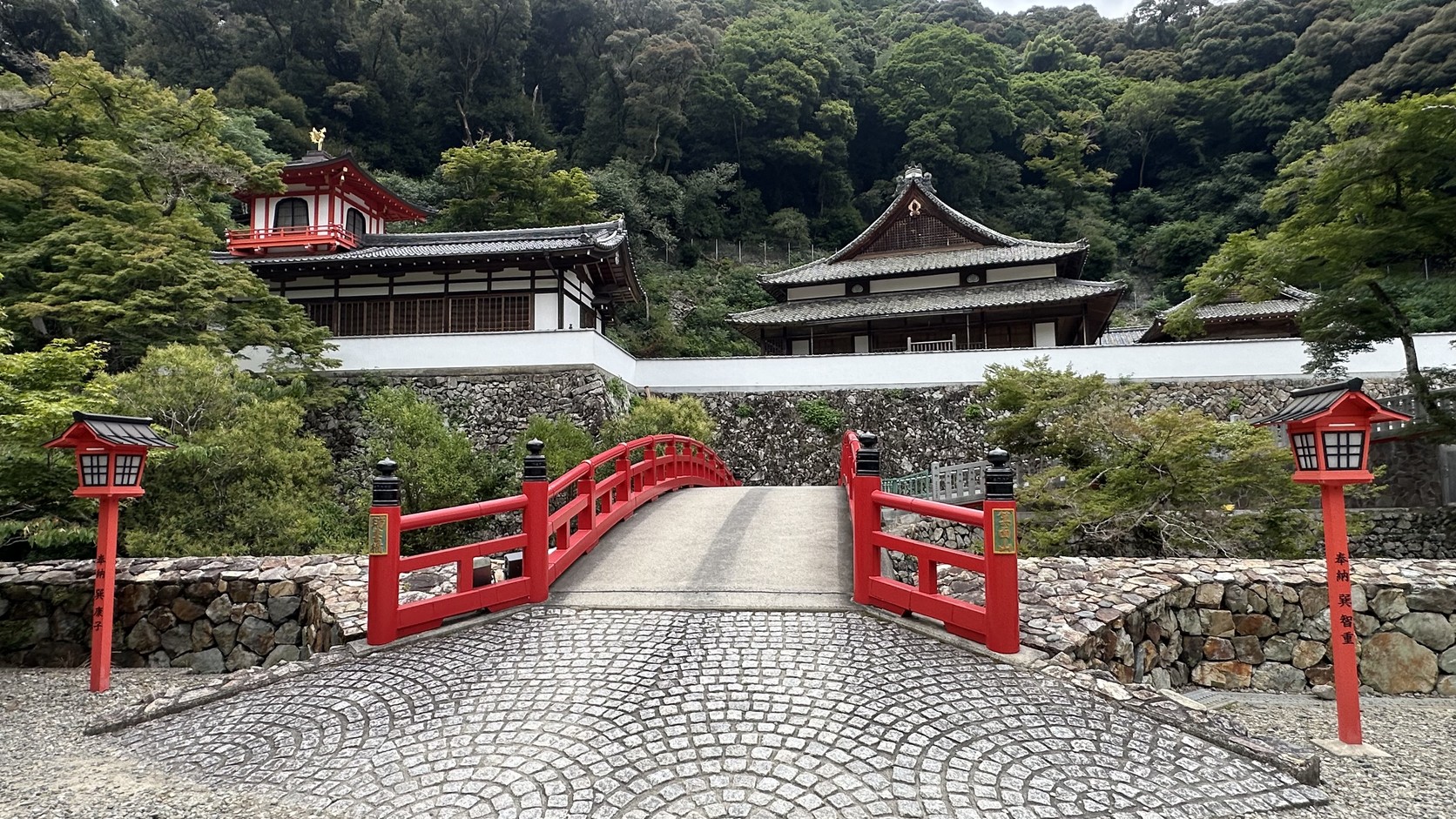 瀧安寺境內的朱紅色拱橋與本殿，背後是濃密的山林