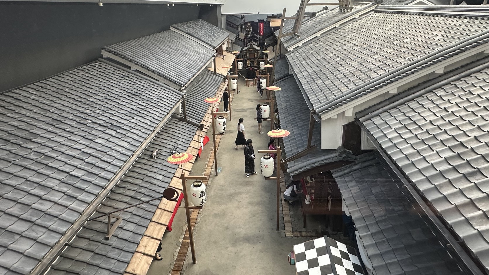 俯瞰江戶街區的窄巷與屋頂，巷子裡有撐傘與穿和服的遊客