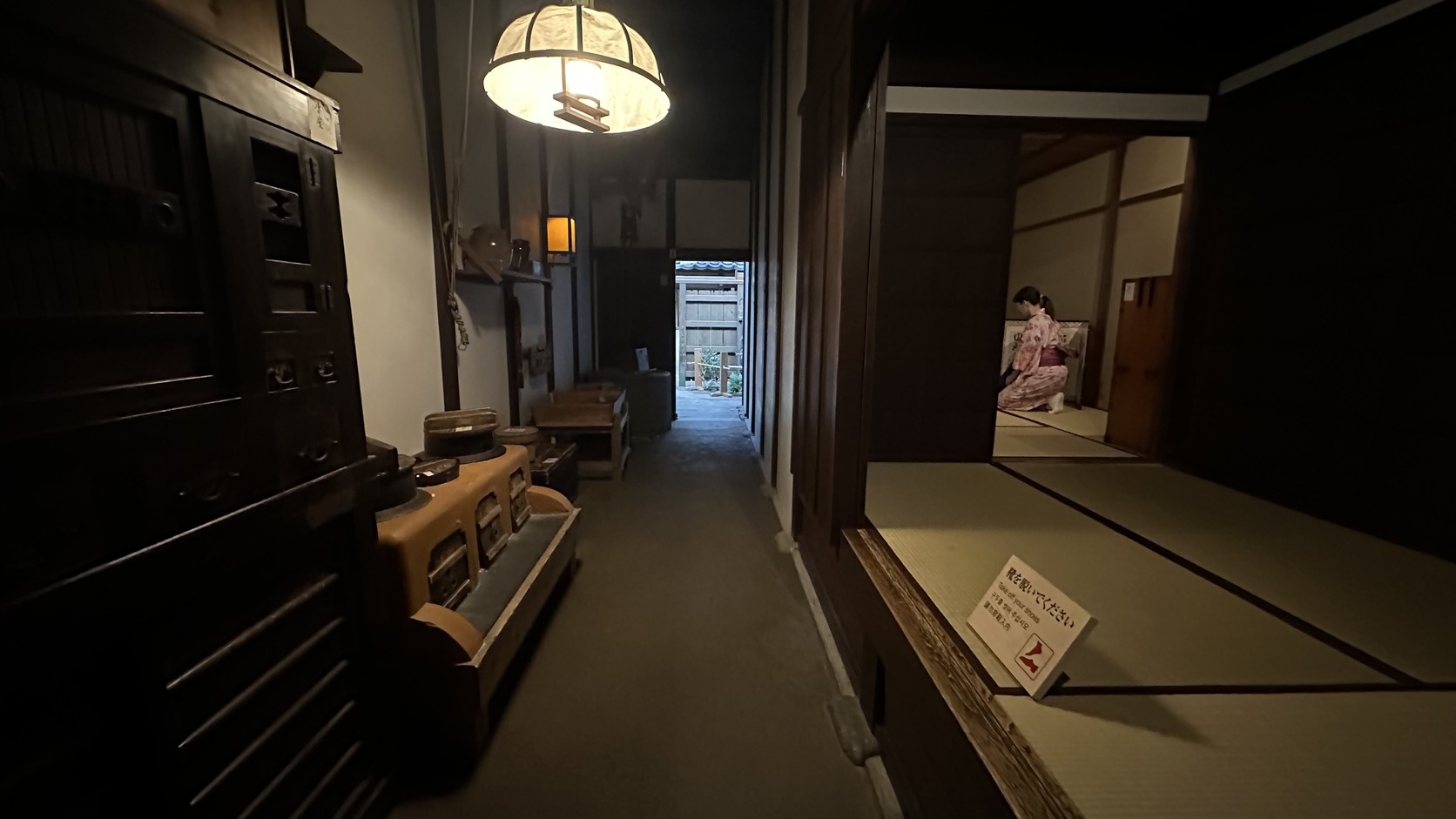 町屋裡狹長的通道與榻榻米房間，遠處有穿和服的遊客