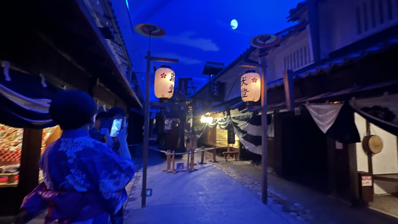 夜景模式下的江戶街道，天空出現月亮，穿浴衣的遊客在拍照