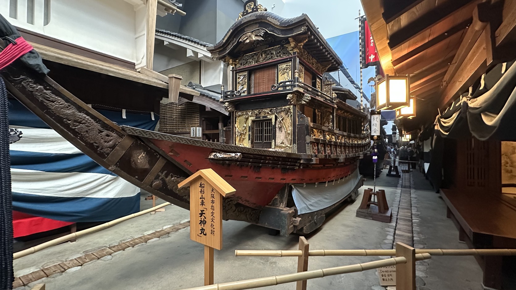 船形山車「天神丸」停放在街道中，前方木牌標示大阪市指定文化財