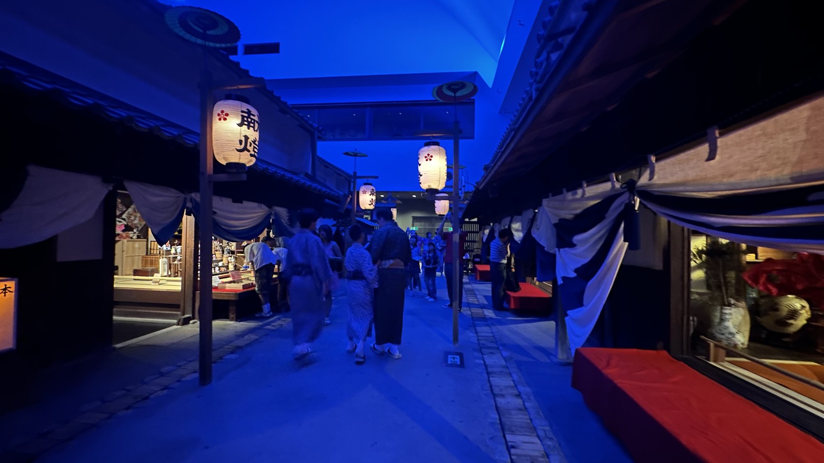 夜晚街道上穿浴衣的遊客走過亮起燈籠的町屋之間