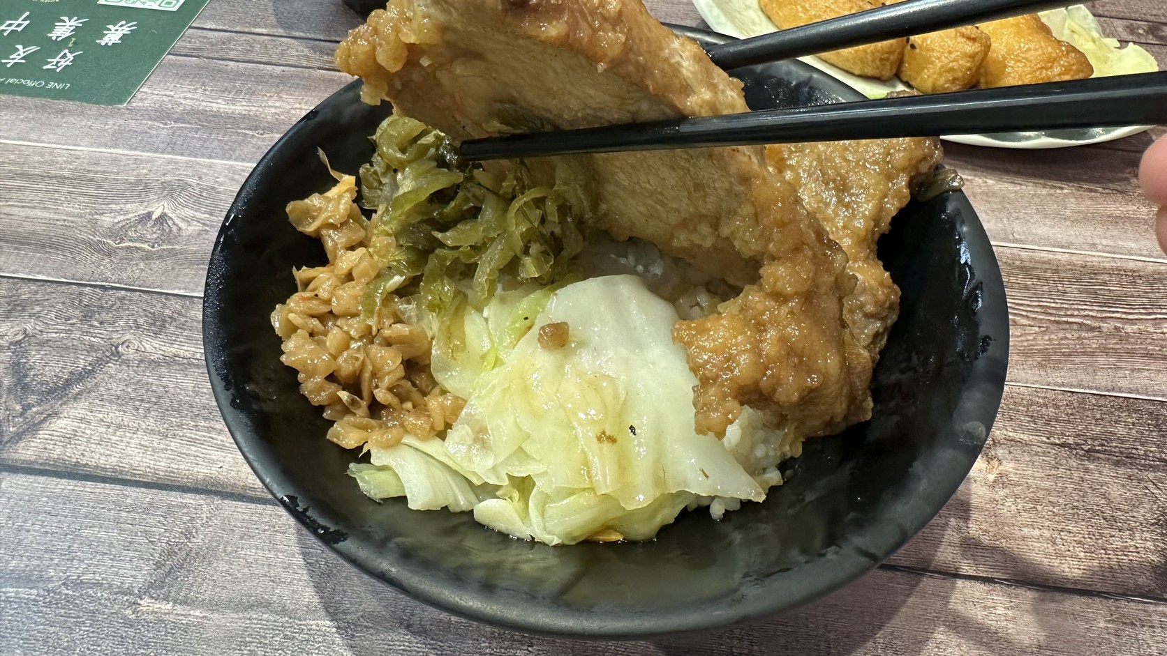 夾起大片排骨露出菜脯鹹菜與白菜的特製排骨飯實拍