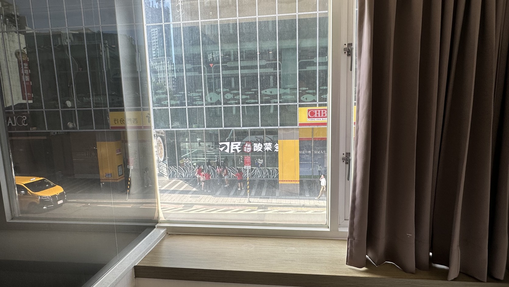窗外白天街景，對街車流與商業大樓實拍