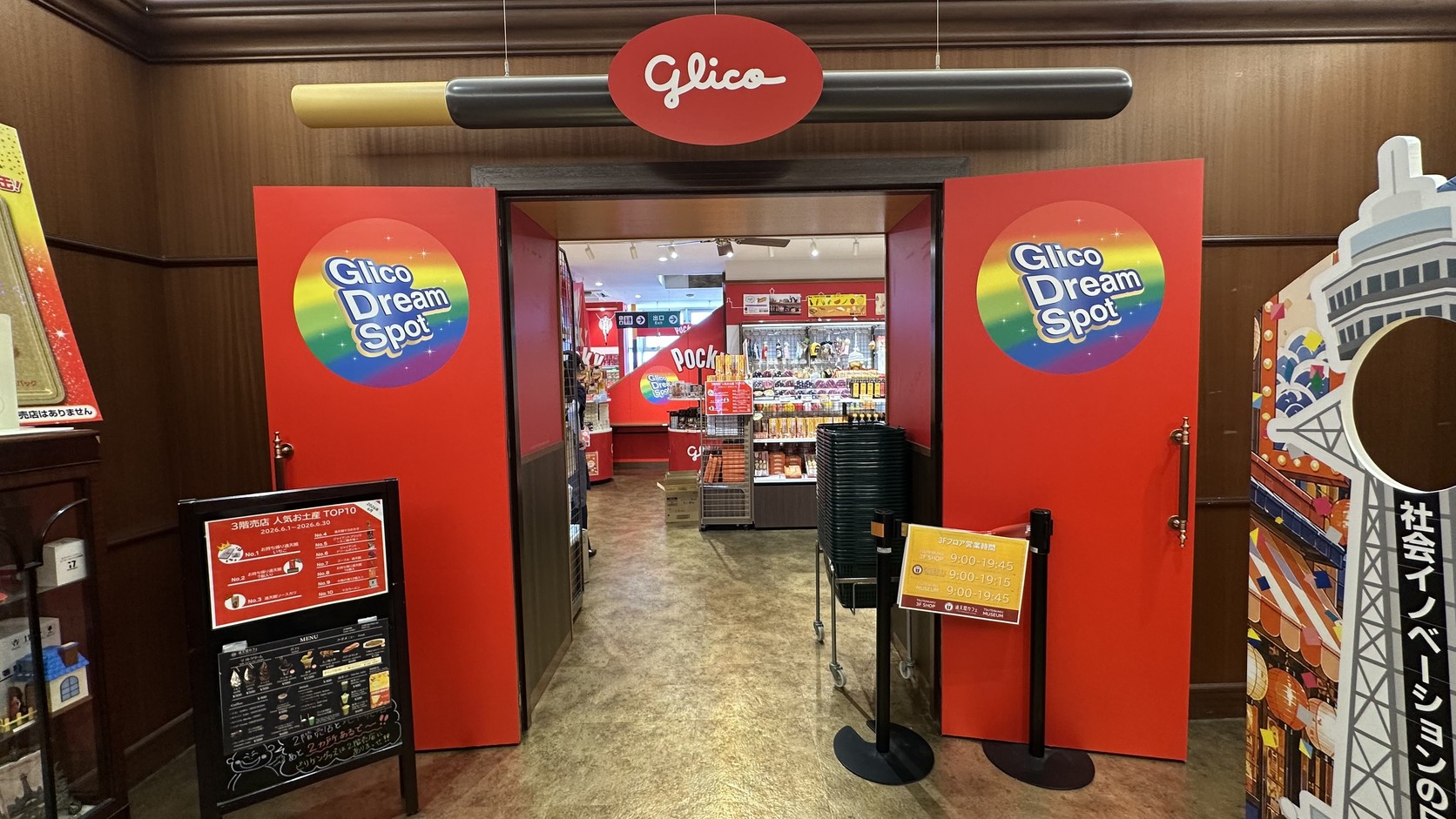 通天閣 Glico Dream Spot 入口，紅色門板與彩虹色圓形標誌，上方橫著一根巨大的 Pocky