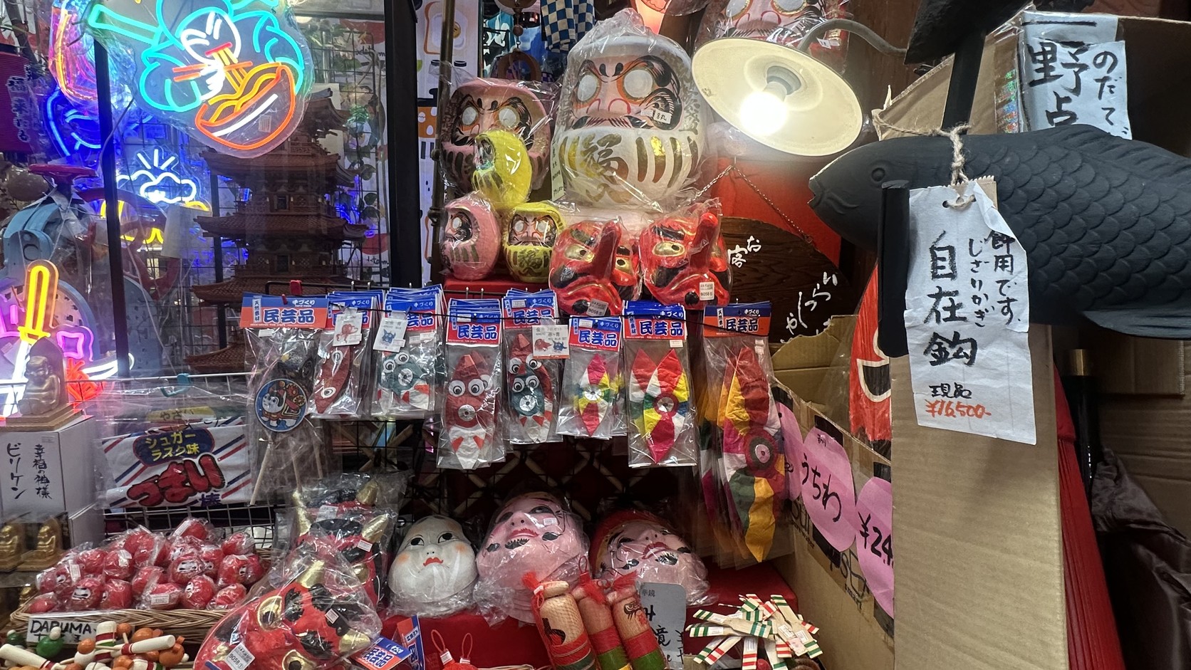 店內架上的達摩、各式面具，以及貼著「民芸品」標籤的小玩具