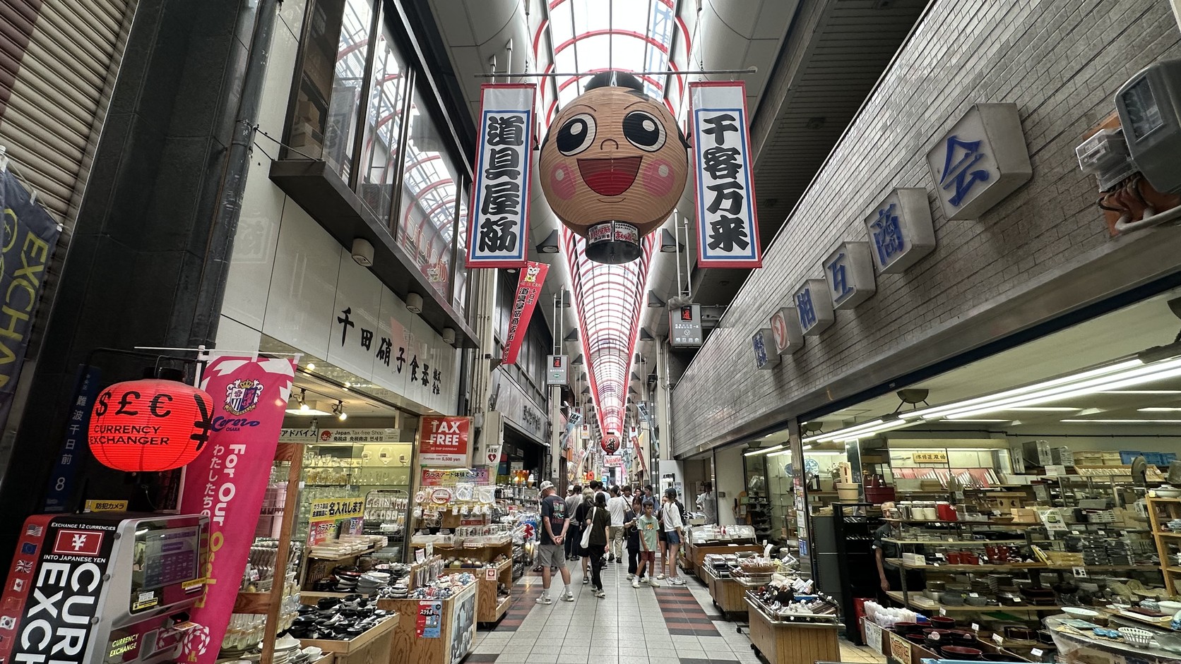 道具屋筋拱廊中懸掛的「道具屋筋」「千客万来」吊旗與笑臉紅燈籠,兩側是店舖與往來人潮