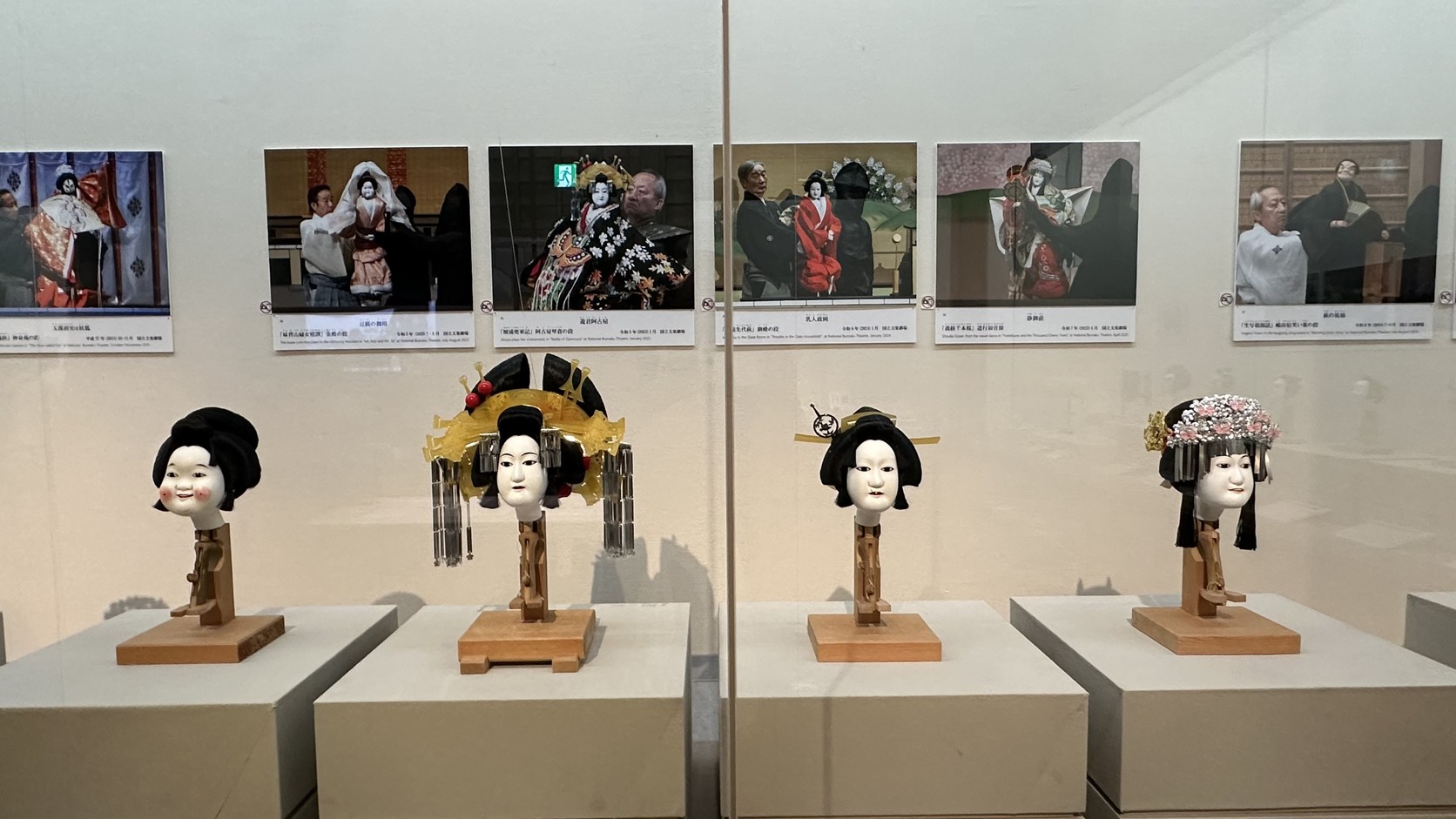 展示區的女形人偶頭，有各種髮型與華麗髮飾，上方是演出劇照