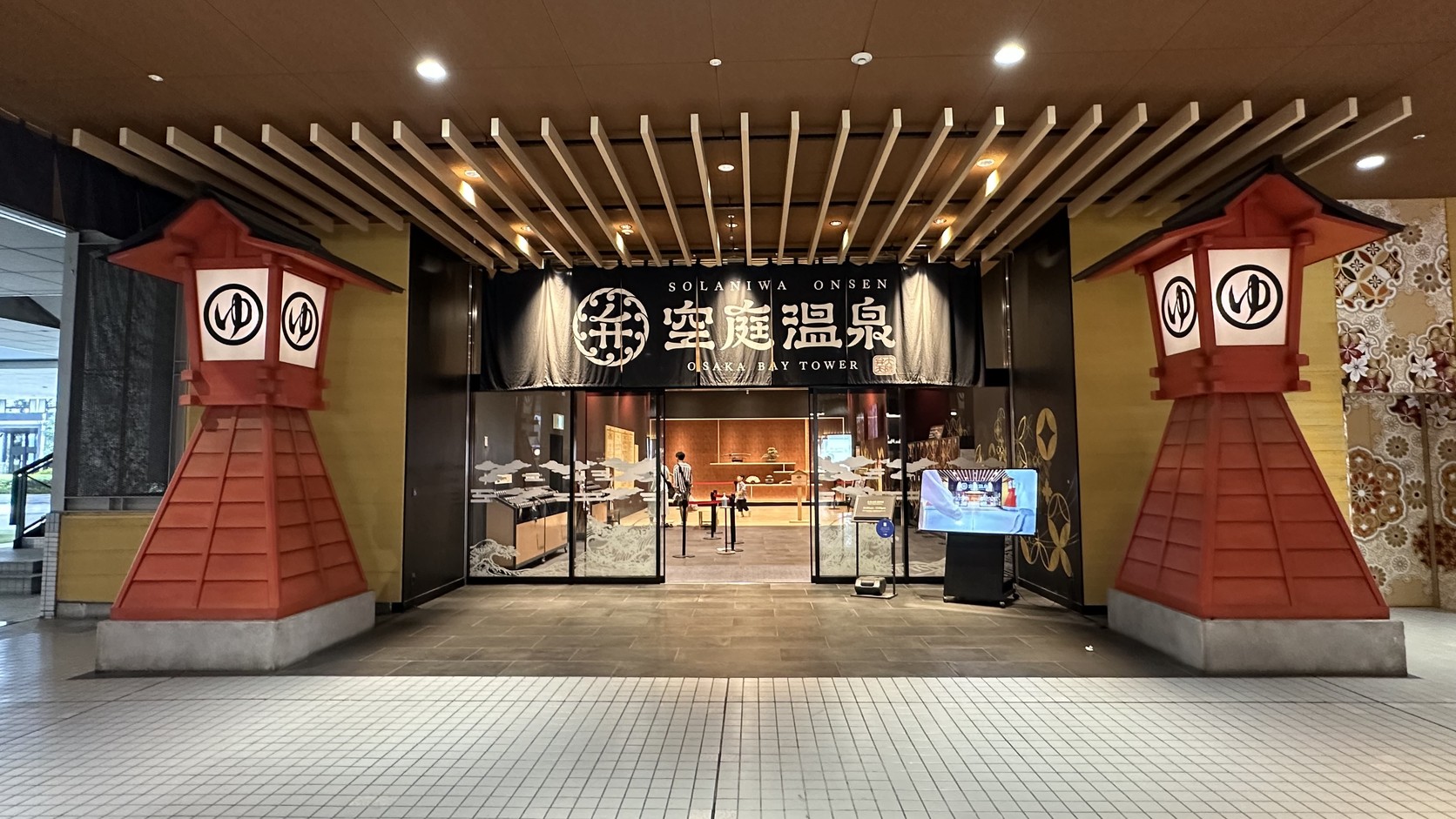 空庭溫泉入口：兩側各有一座寫著「ゆ」的紅色大燈籠，中間是「空庭温泉 OSAKA BAY TOWER」的暖簾