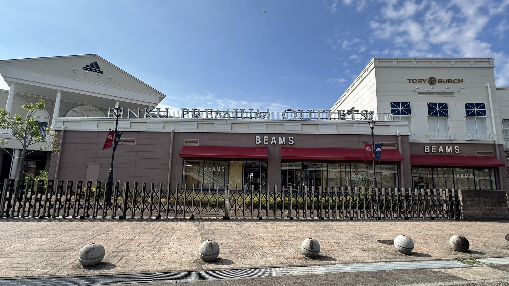臨空 Premium Outlets 正門：RINKU PREMIUM OUTLETS 招牌下方是 BEAMS 店面，前方整排伸縮圍欄拉起