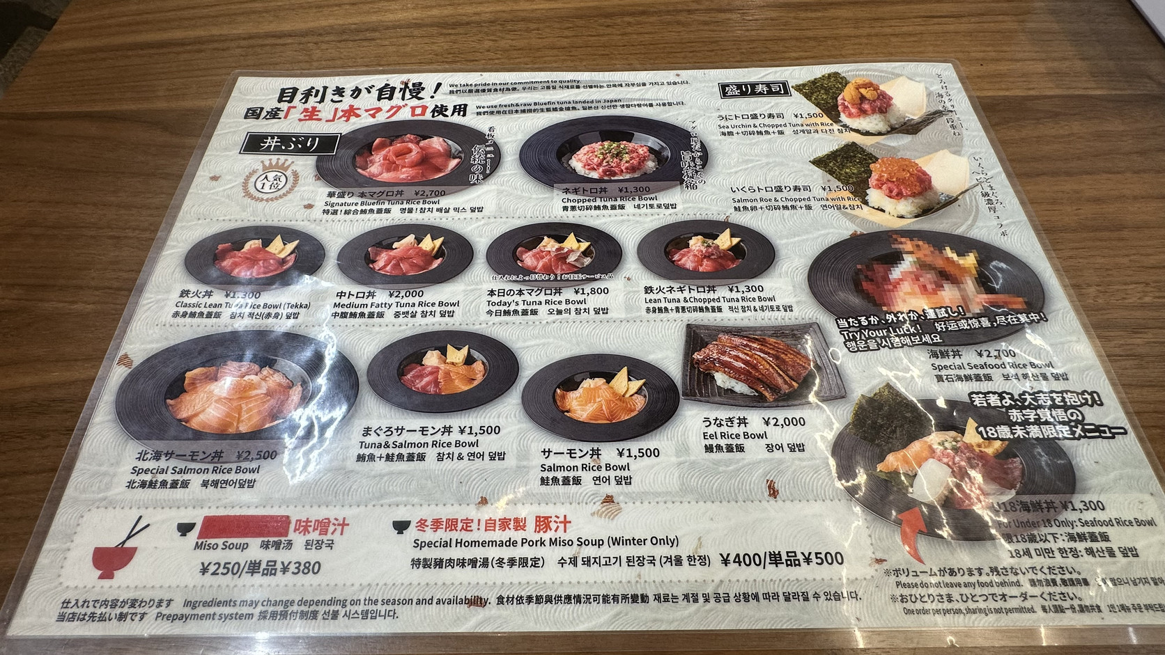 ENTOKI 桌上的多語言圖片菜單，列出丼飯與盛り寿司的照片與價格，並註明先付款制與一人一份