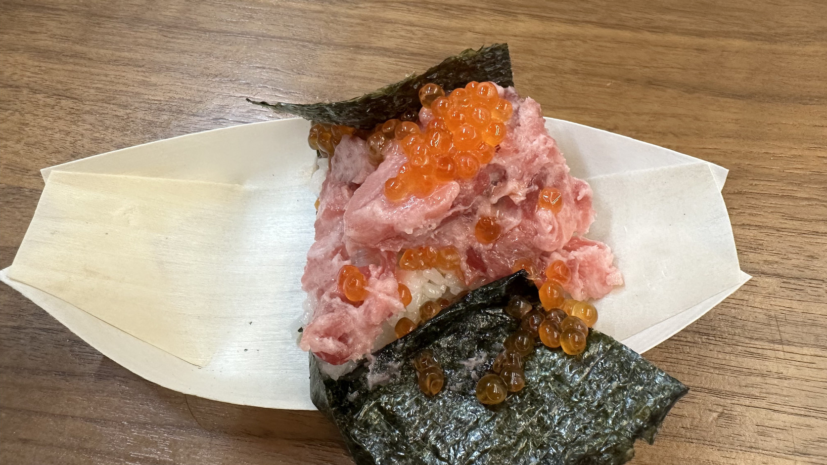 吃到一半的いくらトロ盛り寿司，鮪魚碎肉仍保留魚肉質地，鮭魚卵散落在飯與海苔上