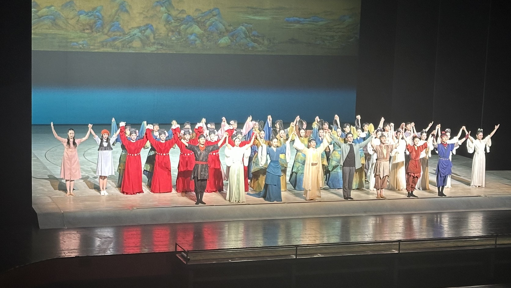 謝幕畫面：全體演員在舞台上舉手致意，背景是《千里江山圖》投影與青藍色天幕