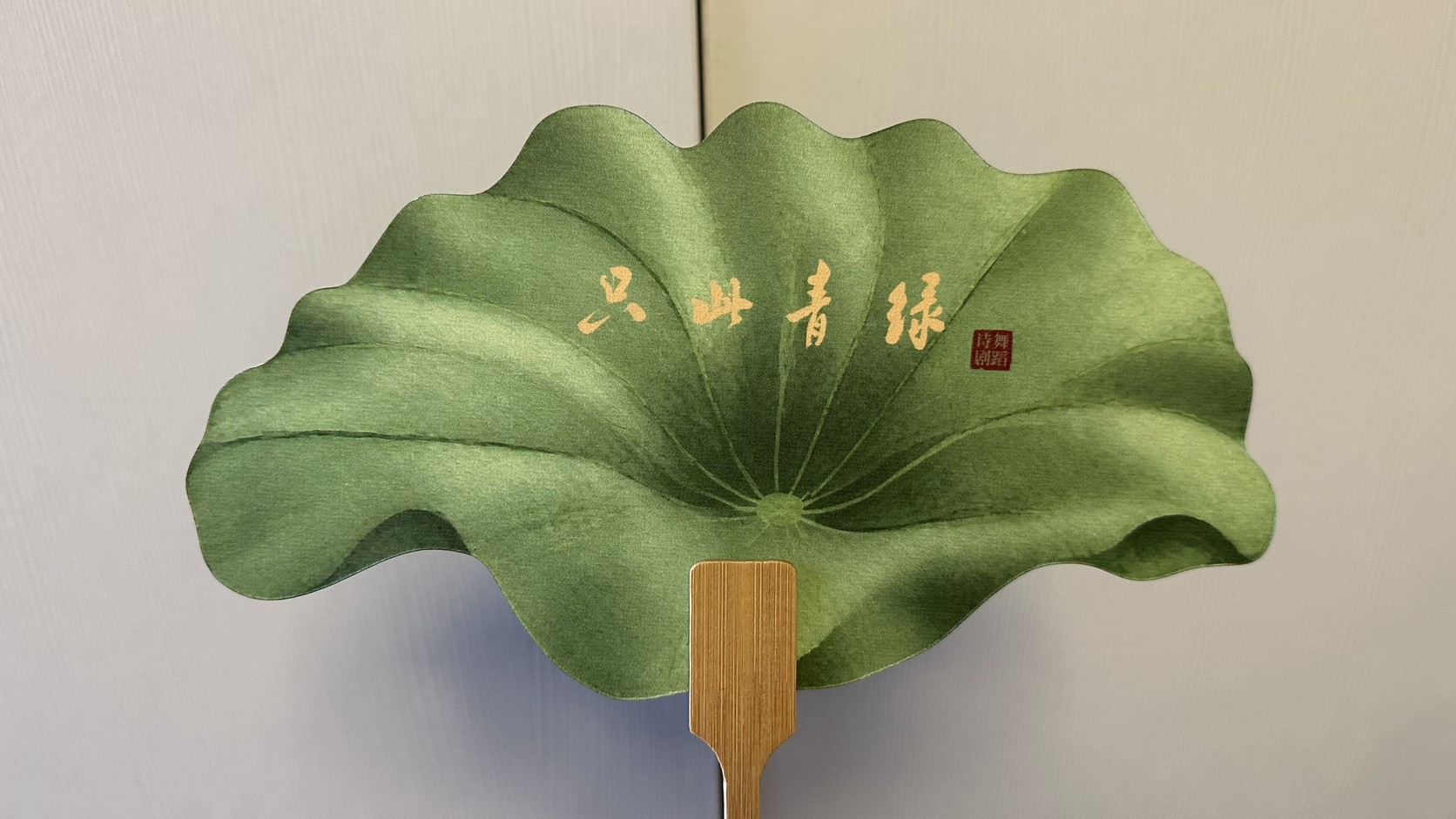 荷葉形團扇：綠色扇面上有金色《只此青綠》書法與紅色詩舞劇印章，於演出隔日 2026 年 8 月 23 日拍攝