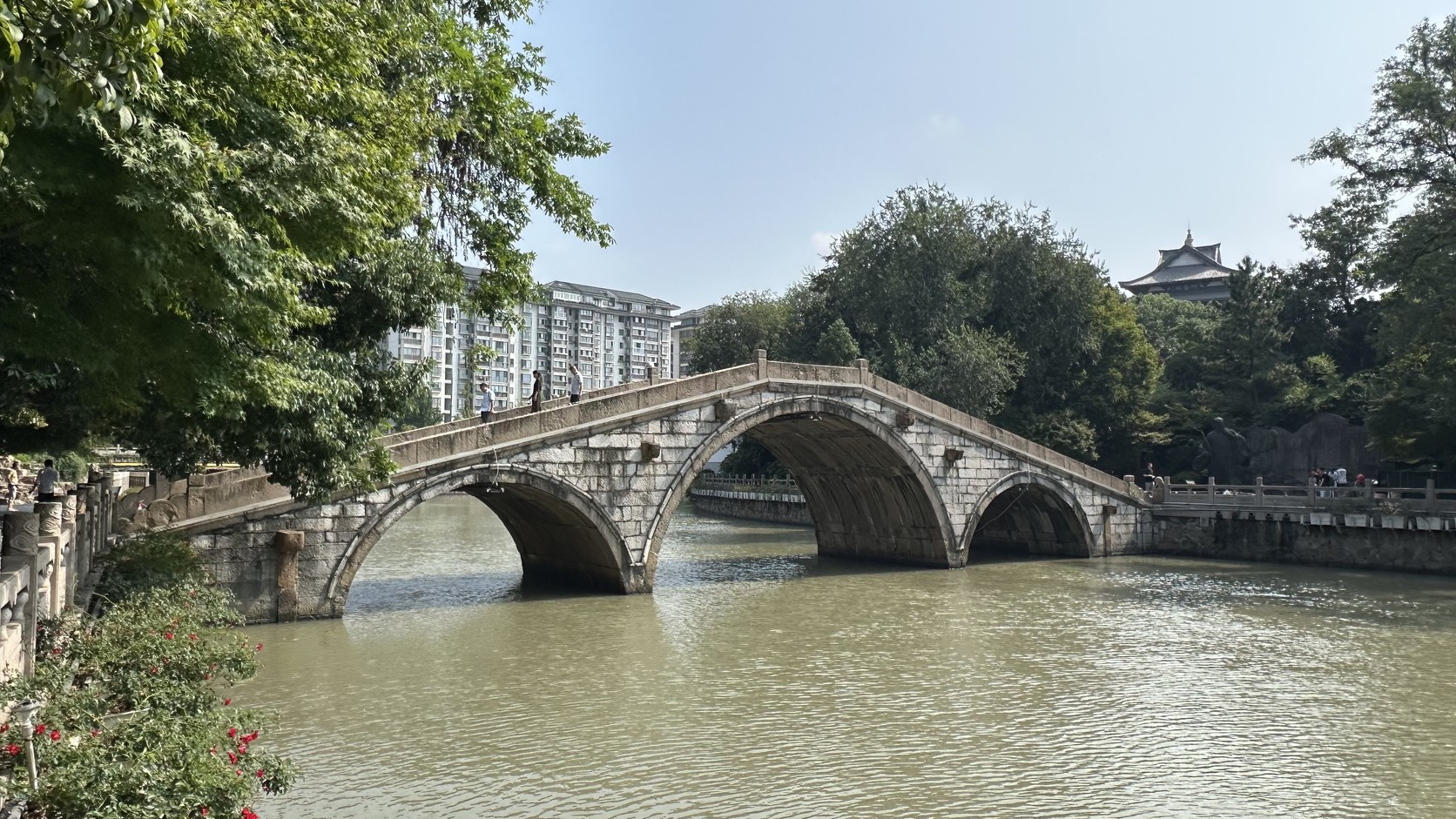三孔石拱橋廣濟橋橫跨古運河，遠處可見仰蘇閣屋頂