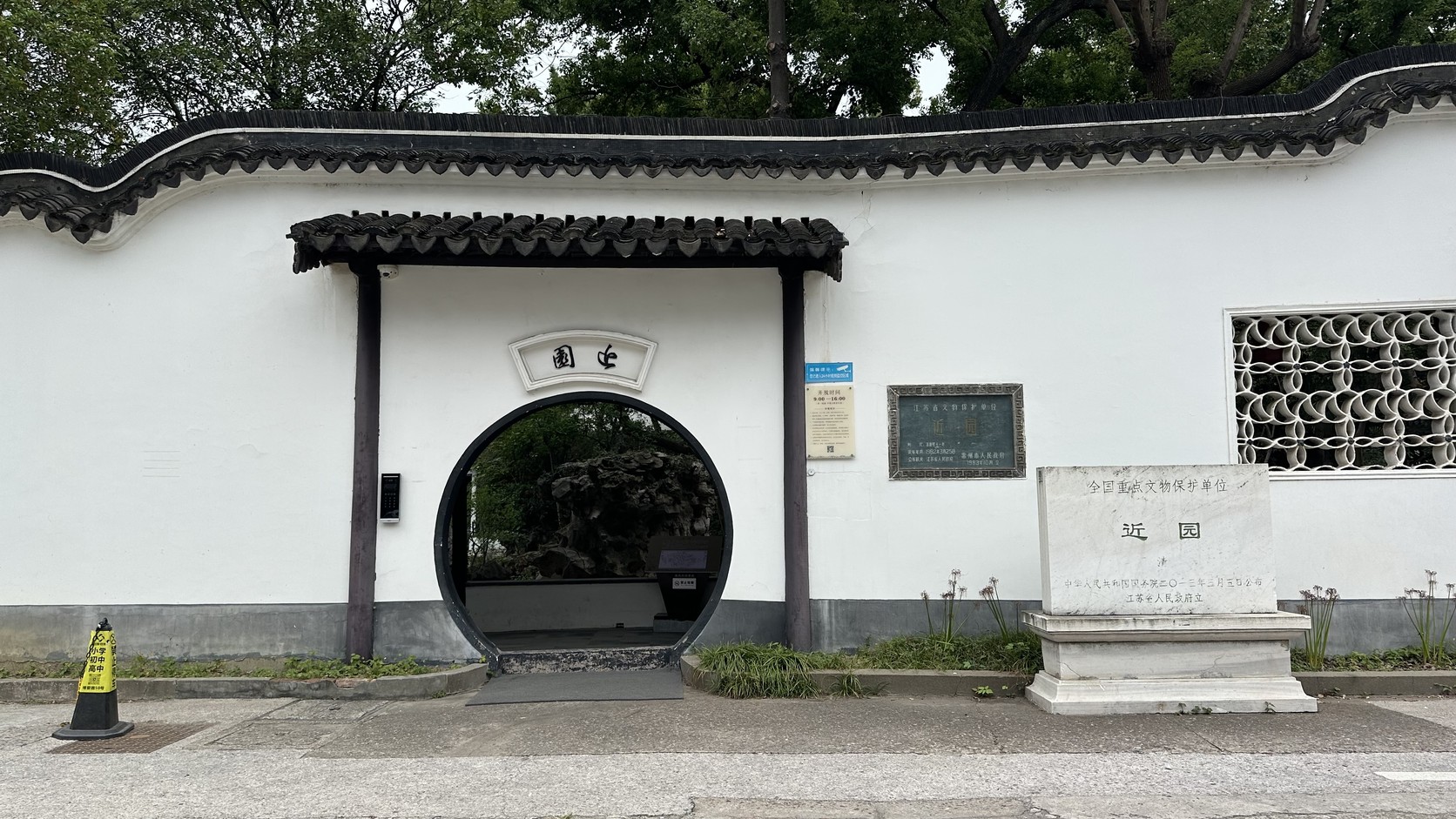 白牆圓形月洞門入口，門額題「近園」，旁邊立著全國重點文物保護單位石碑