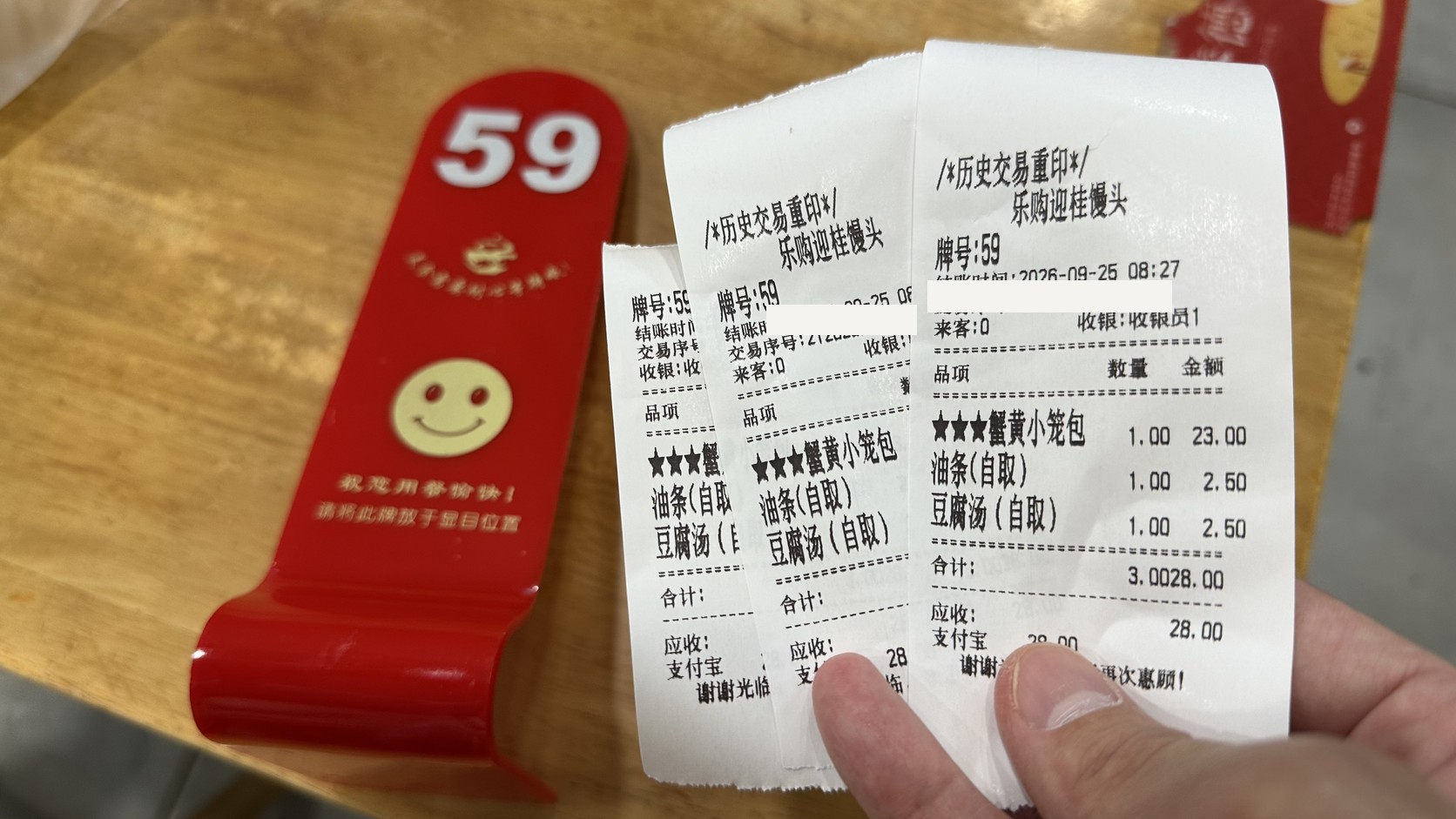 59號取餐牌與三張取餐單，單據列有蟹黃小籠包23元、油條2.5元、豆腐湯2.5元，合計28元
