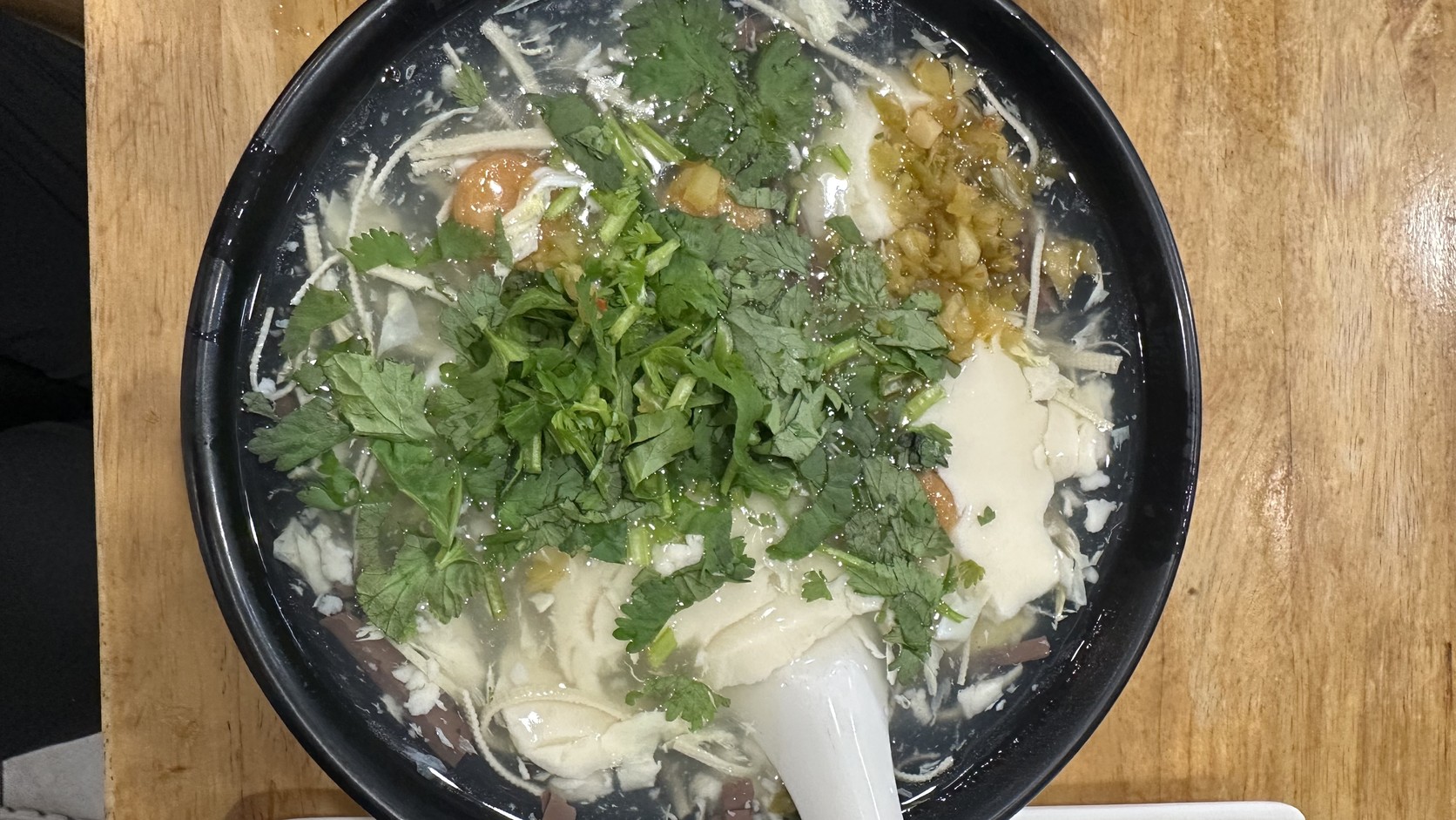 一碗豆腐湯，表面鋪滿香菜，底下是滑嫩的豆花