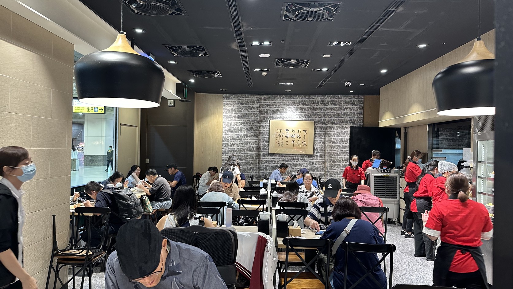 朱記店內用餐環境，黑色吊燈、灰色磚紋牆與座位區，服務人員在桌間走動