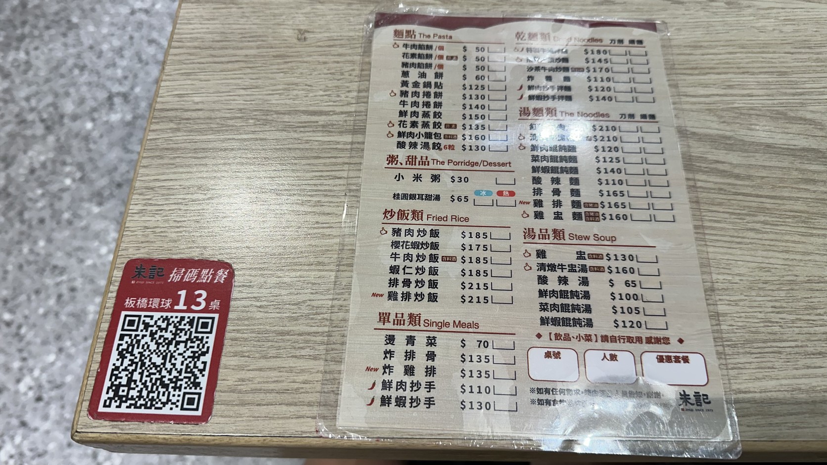 朱記桌上的紙本菜單，列出麵點、粥品、炒飯、乾麵與湯麵的價格