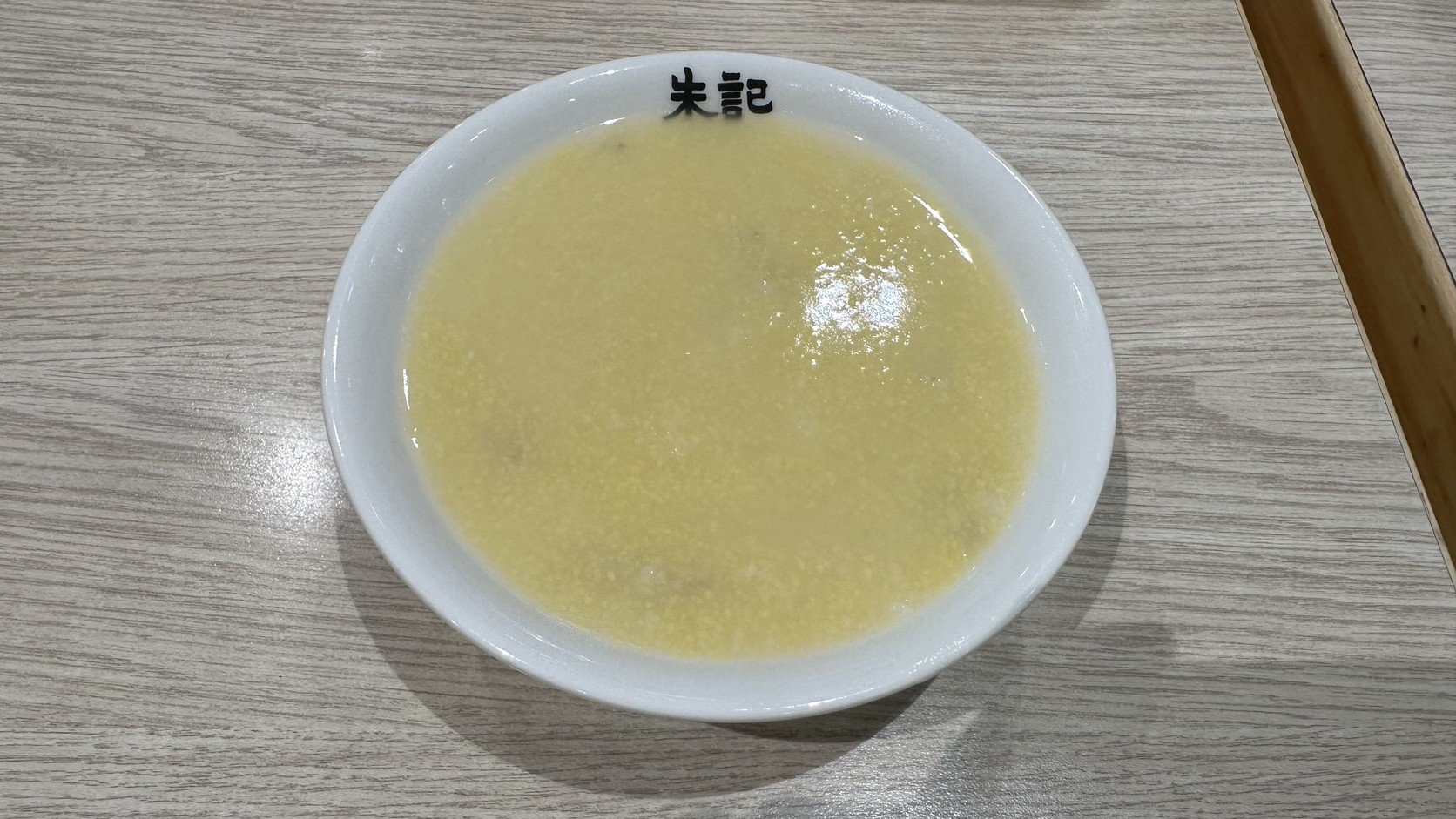 白瓷碗盛裝的朱記小米粥，呈淡黃色