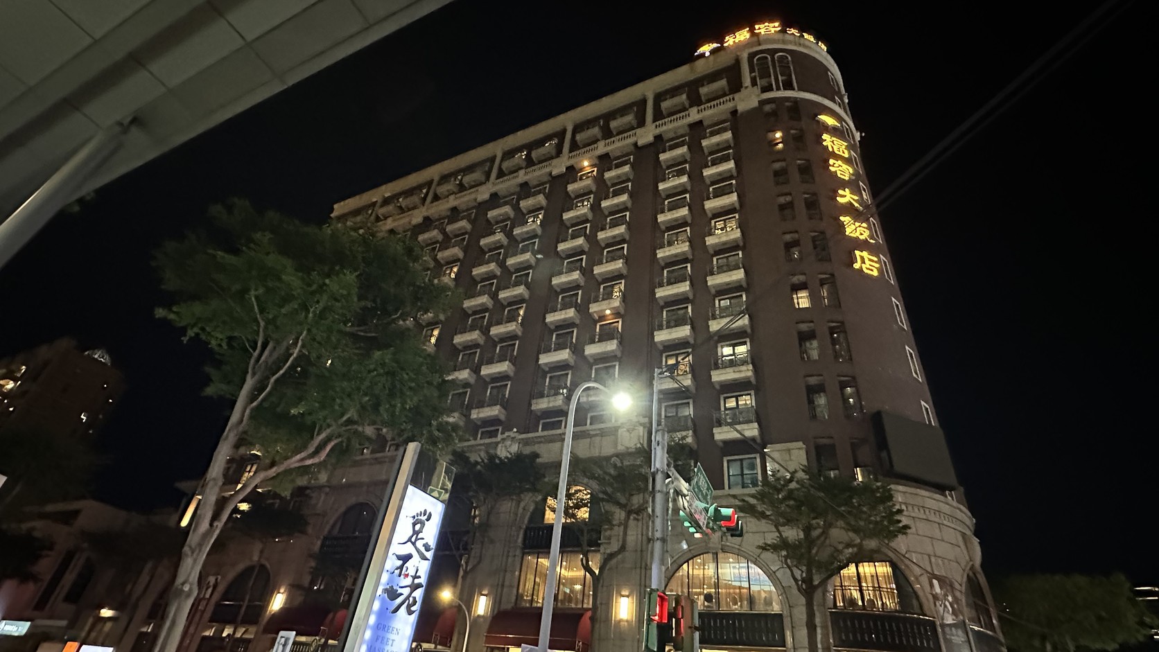 福容大飯店桃園夜間外觀，深色外牆沿街展開，轉角呈圓弧形，頂樓亮著黃色招牌