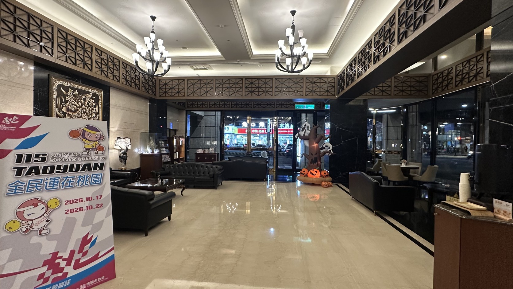福容大飯店桃園一樓大廳，寬敞的接待空間、吊燈、深色木質格紋與黑色沙發