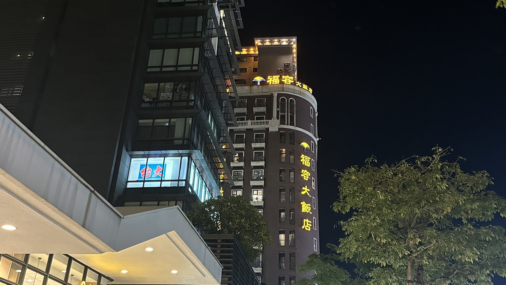 從街角仰望夜晚的福容大飯店高樓與頂樓黃色招牌