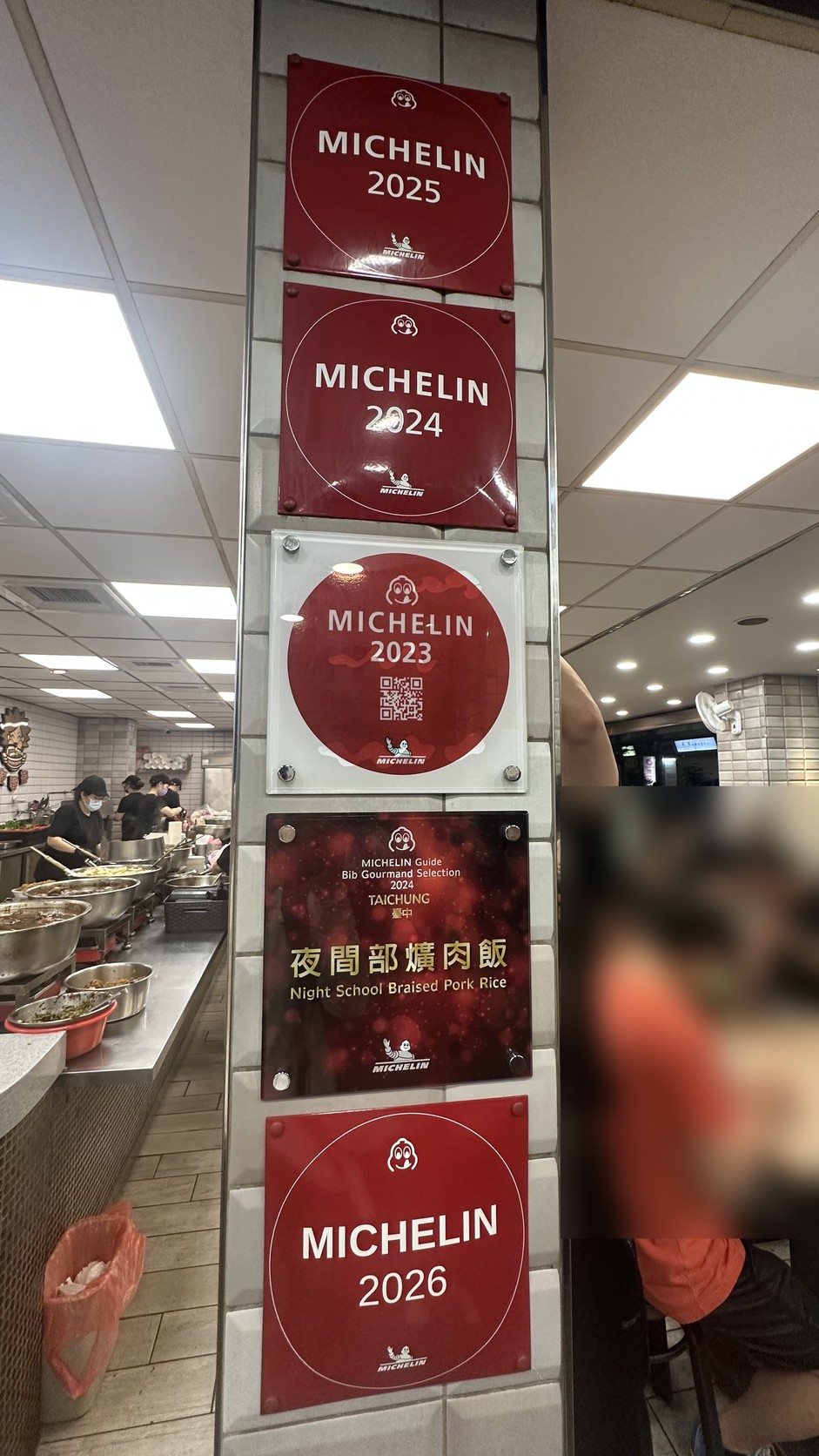 店內柱子上由上而下掛著 2025、2024、2023 米其林牌、2024 Bib Gourmand Selection Taichung 牌與 2026 米其林牌