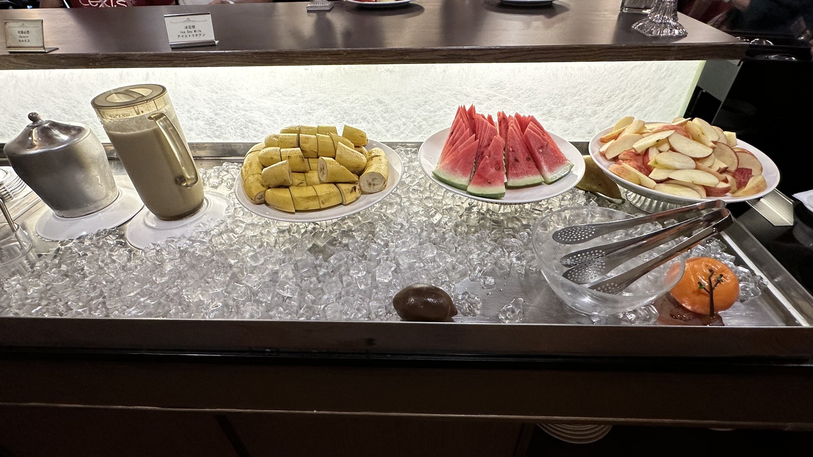 早餐水果區：切好的香蕉、西瓜與蘋果片擺在碎冰上