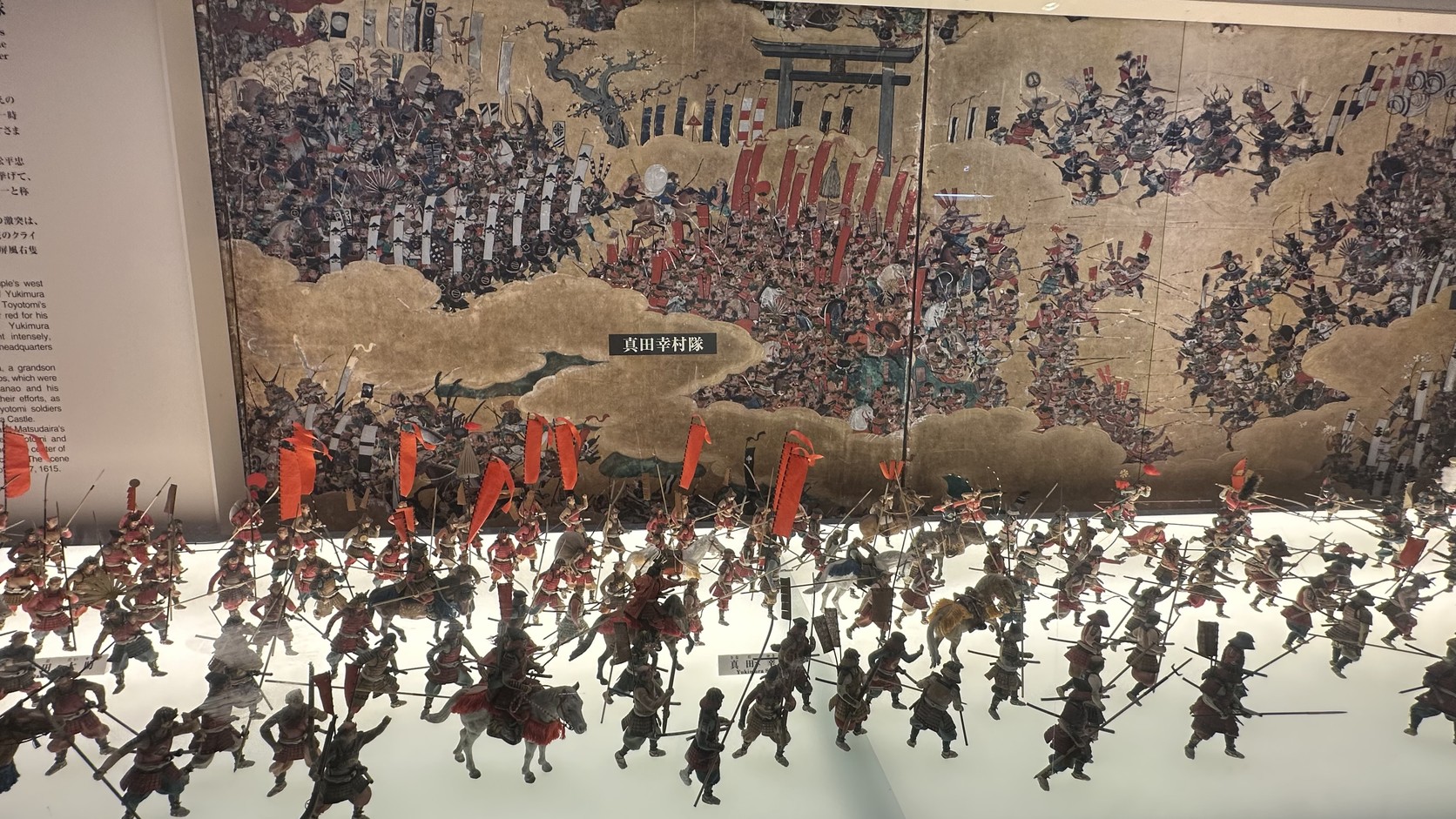 五樓大坂夏之陣立體模型，前方是密集的人偶部隊，標示牌寫著「真田幸村隊」，後方是屏風畫面