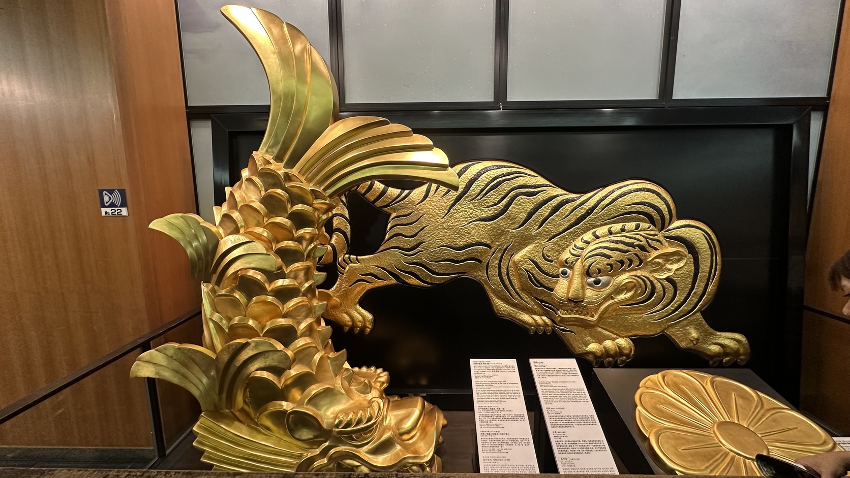二樓展示的金鯱、伏虎與菊紋金色裝飾，旁邊有說明牌