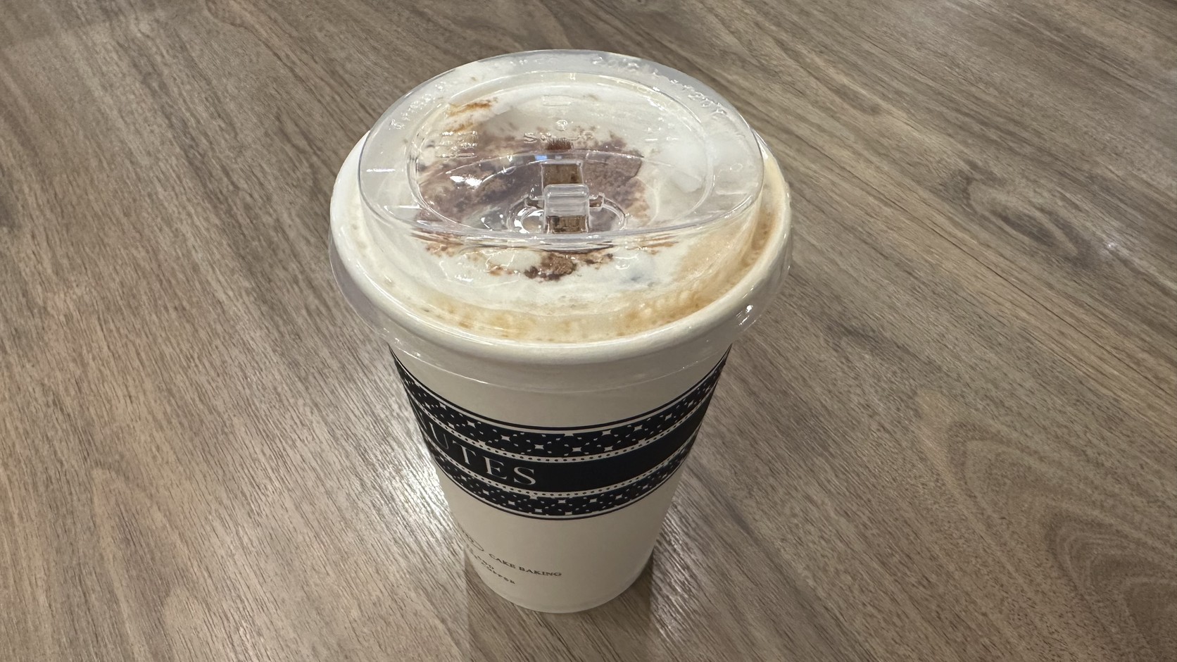 黑糖雪霜奶茶外觀：白色雪霜奶蓋與深褐色黑糖裝飾，黑白色調杯身