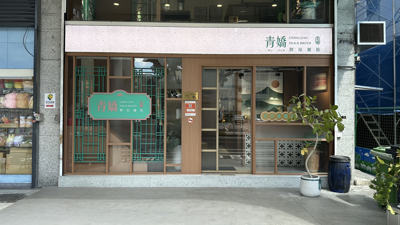 青嬌膠原麵館店面：粉紅色招牌、青綠色窗格與木框玻璃門