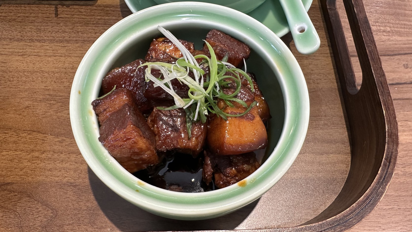 東坡紅燒肉特寫：青瓷小碗裡盛著方塊五花肉，上面撒著蔥絲