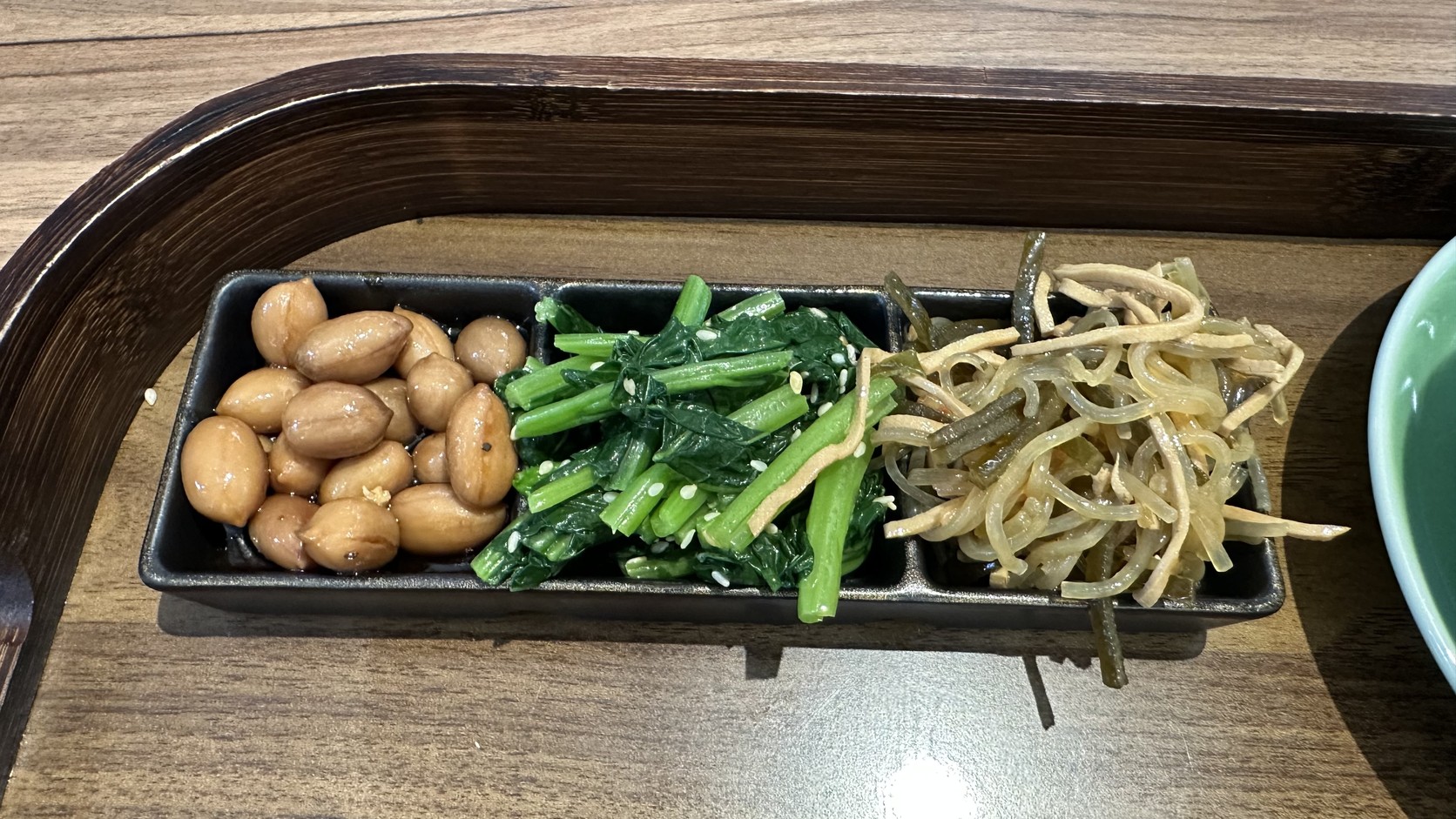 三樣附餐小菜：醬色花生、撒白芝麻的青菜與淺色細絲涼拌小菜