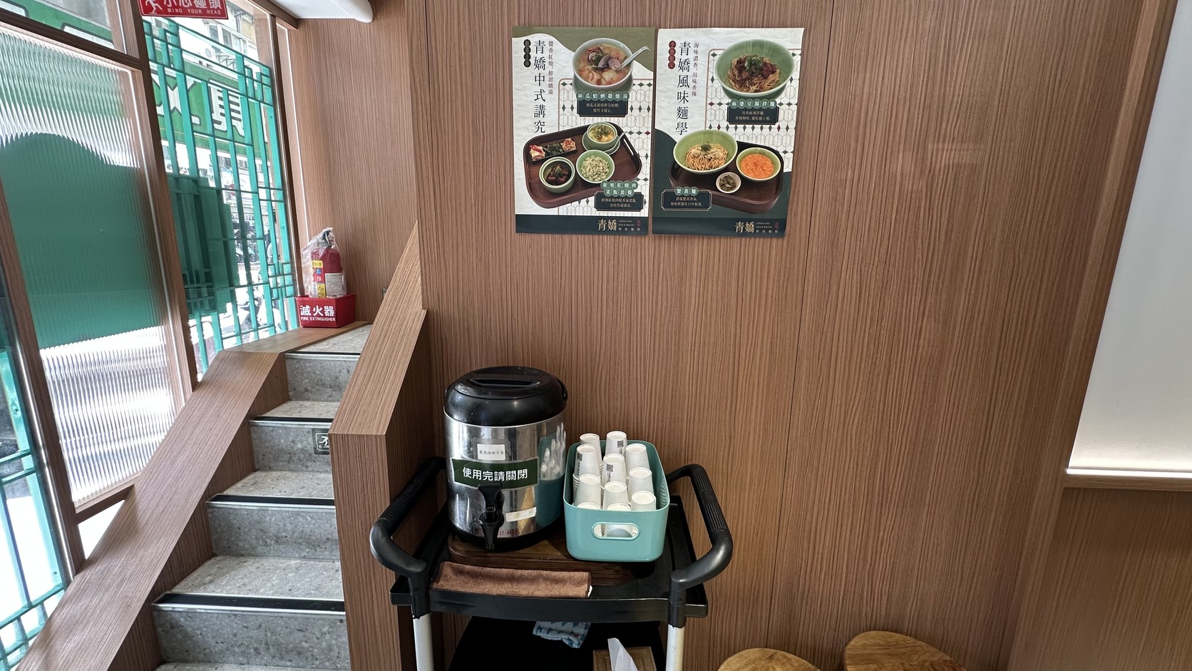 樓梯旁的自助決明子茶區，保溫桶與杯子放在推車上