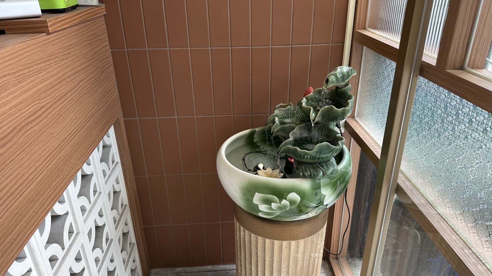 門口的荷葉造型陶瓷流水盆景，清水沿葉面流入繪有花葉的圓盆