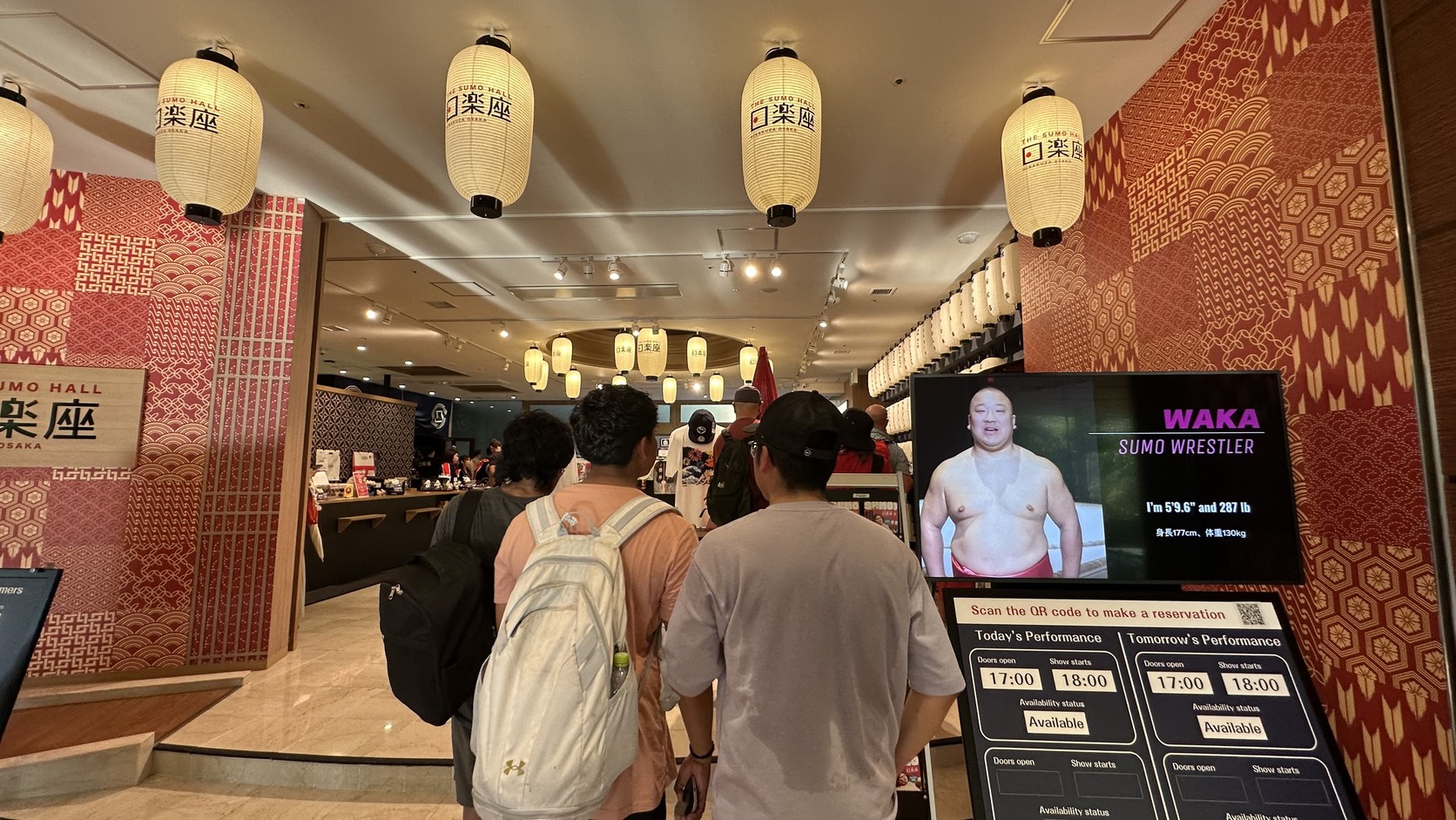 日樂座入口的櫃檯與排隊入場的觀眾，旁邊螢幕顯示力士介紹與場次時間