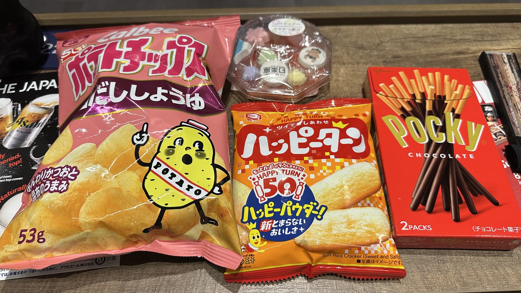 零食袋的實際內容，有高湯醬油口味洋芋片、Happy Turn 米果、Pocky 與日式小點心盒