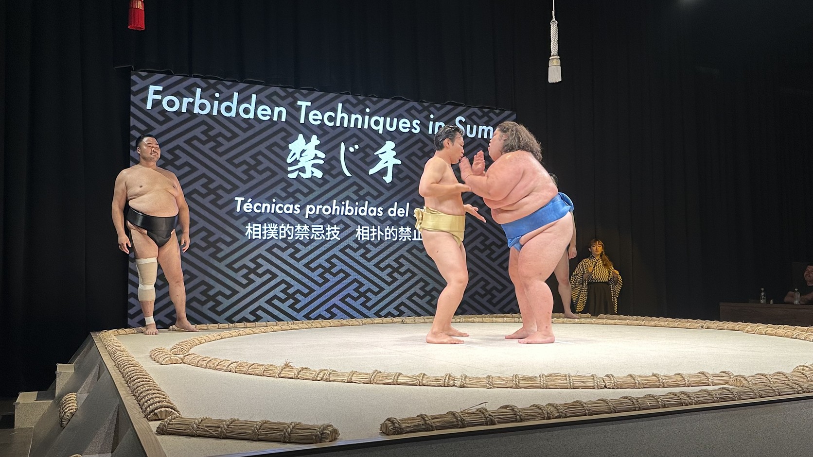 力士以誇張動作示範禁手，螢幕顯示 Forbidden Techniques in Sumo
