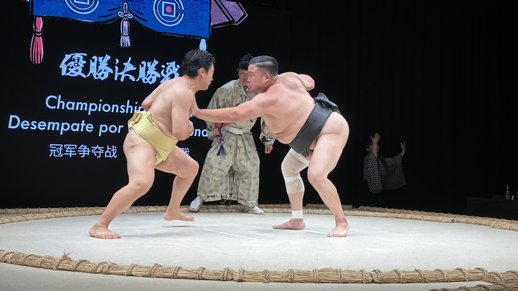 優勝決勝戰中兩位力士在土俵上推擠，螢幕顯示 Championship Playoff
