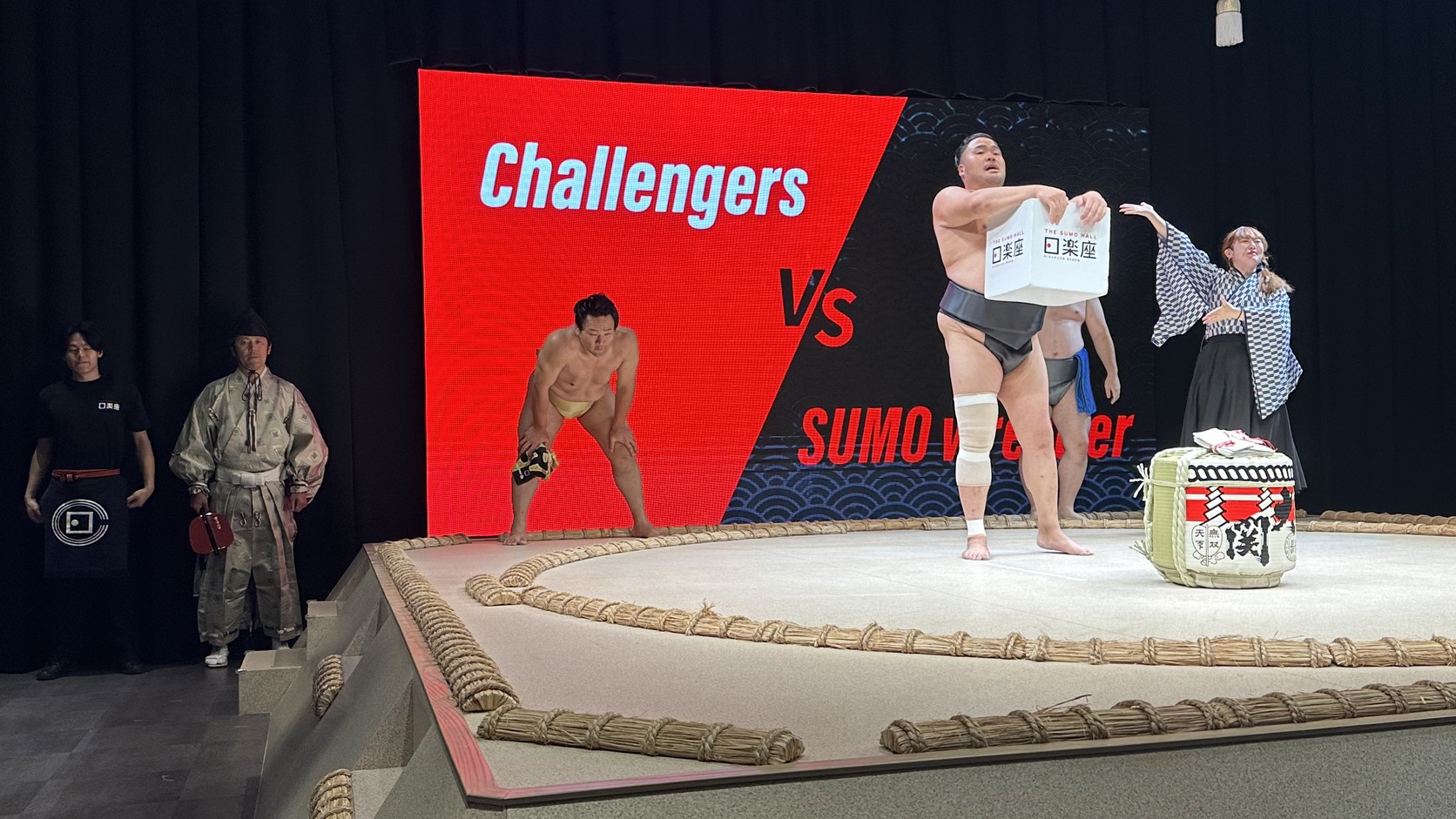 螢幕顯示 Challengers VS Sumo Wrestler，旁邊是抽籤用的木箱